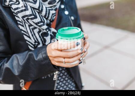 Boisson chaude dans la tasse à emporter dans les mains féminines à l'extérieur à l'automne Banque D'Images