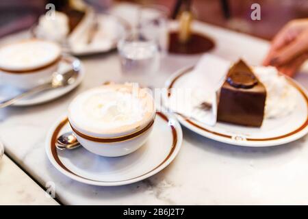 24 MARS 2017, VIENNE, AUTRICHE : le gâteau authentique de Viennese Sacher Torte servi avec de la crème fouettée et une tasse de café au Sacher Hotel Cafe Banque D'Images