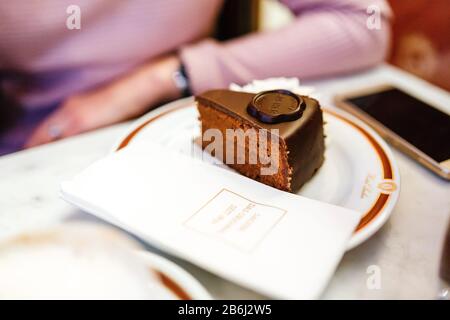 24 MARS 2017, VIENNE, AUTRICHE : le gâteau authentique de Viennese Sacher Torte servi avec de la crème fouettée au café Banque D'Images