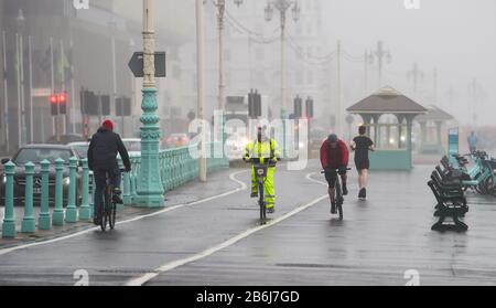 Brighton UK 11 Mars 2020 - Cyclistes dans la brume le long du front de mer de Brighton ce matin sur un démarrage humide de la journée sur la côte sud . Crédit: Simon Dack / Alay Live News Banque D'Images