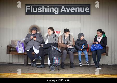 Quartier de New York Brooklyn Bushwick quartier Flushing Avenue station de métro passagers assis sur un banc en bois Banque D'Images