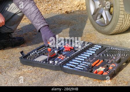 Сar conducteur utilisant différents outils de réparation pour réparer et diagnostiquer une voiture. Jeu d'outils près de l'auto. Divers outils dans la boîte, la fermeture. Banque D'Images