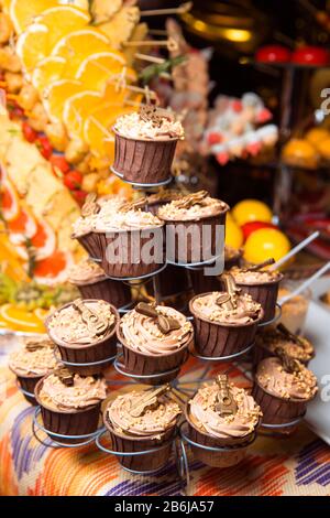 Des cupcakes au chocolat fraîchement préparés, décorés de crème et de boules, se tiennent sur un stand. Atmosphère de vacances, dessert appétissant . Bonbon. Banque D'Images