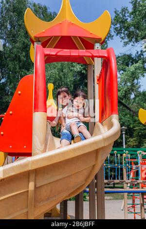 Deux mignonnes petites filles s'amuser sur une aire de l'extérieur en été Banque D'Images
