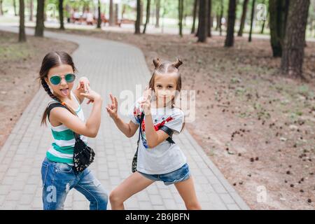 Deux Petites filles Élégantes dans des lunettes de soleil ayant l'extérieur amusant Banque D'Images