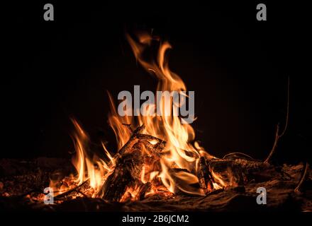 Belle photo de feu de joie isolé avec des flammes vives de couleur jaune et orange représentant une combustion incomplète de bois de chauffage pendant les nuits d'hiver Banque D'Images