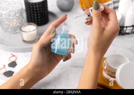 Femme avec manucure Appliquer des cosmétiques sur sa main sur la table en marbre Banque D'Images