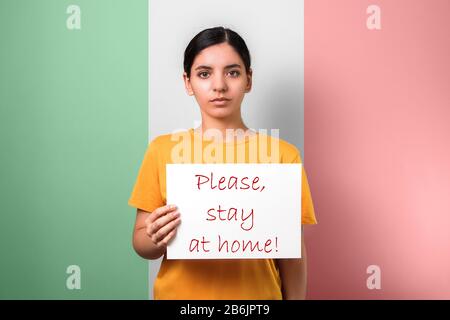 coronavirus conseil de rester à la maison. femme tenant un placarde contre le drapeau italien demandant aux gens de ne pas quitter leurs maisons Banque D'Images