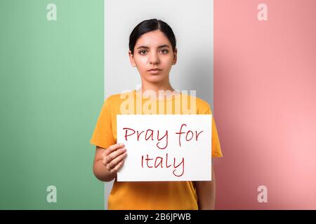 Priez pour l'Italie. Épidémie de coronavirus rassemblant des gens ensemble. Femme tenant un placarde contre le drapeau italien Banque D'Images