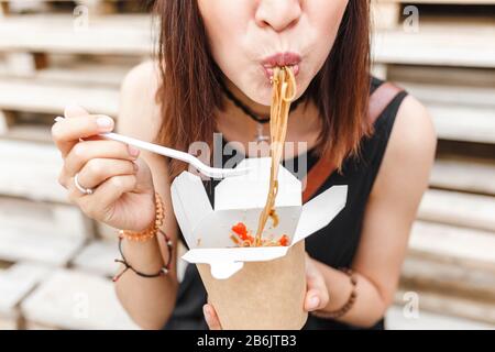 Une belle femme mange de la restauration rapide asiatique à emporter. Délicieuses nouilles wok Banque D'Images