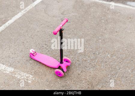 Un petit scooter rose pour les enfants sur le trottoir d'asphalte Banque D'Images