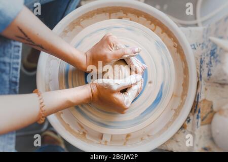 Vue de dessus des mains avec la fabrication d'argile d'un pot en céramique sur la roue de poterie, passe-temps et loisirs avec concept de plaisir Banque D'Images