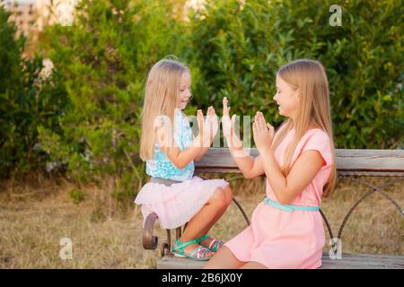 Deux petites filles sœurs embrassant et s'amuser dans le parc. Joyeux enfants filles jouer à l'extérieur. Concept amies. Banque D'Images