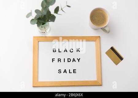 concept commercial et marketing - planche magnétique blanche avec mots de vente de vendredi noir, carte de crédit et tasse de café sur table Banque D'Images