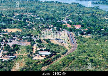 Vue aérienne de la ville touristique de Victoria Falls au Zimbabwe avec la rivière Zambèze en haut. Beaucoup de végétation dans la vue montrant un chemin de fer. Banque D'Images