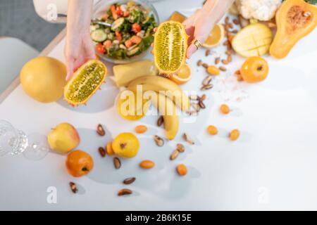 Femme mangeant une salade à la table pleine de légumes et de fruits crus sains, vue sur la culture d'en haut sans visage. Concept de végétarisme, de saine alimentation et de bien-être Banque D'Images