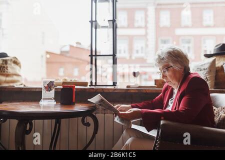 08 juillet 2017, UFA, RUSSIE : une vieille femme lisant un journal dans un café Banque D'Images