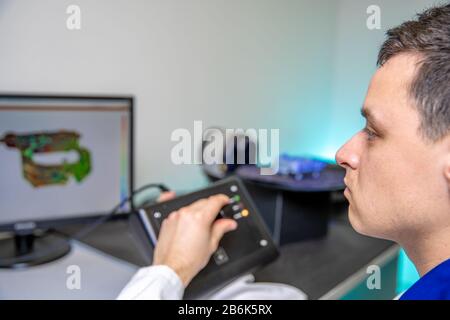 L'ingénieur numérise un composant en plastique de haute qualité avec un scanner tridimensionnel, une plate-forme rotative à l'aide d'un joystick Banque D'Images