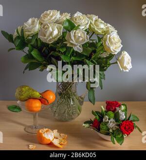 Magnifique bouquet de roses dans une carafe en cristal et une poire avec des tangerines. Toujours la vie. Vintage. Banque D'Images