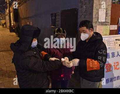 Pékin, Chine. 5 mars 2020. Les travailleurs communautaires vérifient la température corporelle de l'autre à Xin'anli Hutong, dans le district de Dongcheng à Beijing, capitale de la Chine, le 5 mars 2020. Les hutongs de Beijing, le labyrinthe généralement animé des ruelles traditionnelles, sont devenus beaucoup plus silencieux après l'apparition de la nouvelle maladie du coronavirus, ou COVID-19, en Chine. Depuis lors, les travailleurs communautaires, le personnel de sécurité et les bénévoles font de grands efforts pour répondre aux besoins des résidents et lutter contre l'éclosion du virus. Crédit: Chen Zhonghao/Xinhua/Alay Live News Banque D'Images