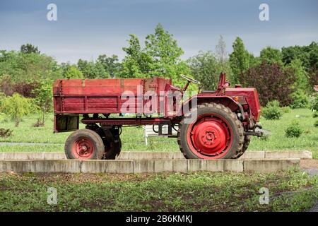 Tracteur rouge stationné dans le jardin, concept agricole et rural Banque D'Images