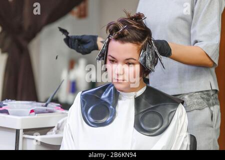 coiffeur colorieuse femme cheveux dans salon de salon de coiffure salon de coiffure, à l'aide de brosse et de feuille, colorant professionnel et concept de traitement Banque D'Images