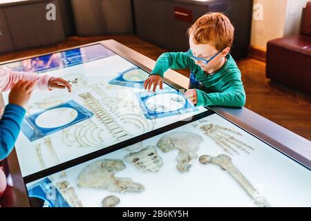 24 MARS 2017, VIENNE, MUSÉE DE L'HISTOIRE NATURELLE, AUTRICHE: Little Red boy prodigy et geek étudient l'anatomie humaine à l'aide d'un ordinateur interactif Banque D'Images