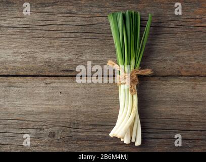 feuilles d'oignon vert frais attachées avec une corde dans un bouquet sur un fond gris en bois, vue de dessus Banque D'Images