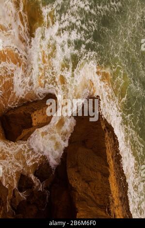 Vagues qui s'écrasent contre les rochers, comme on le voit depuis le sommet d'une falaise. Banque D'Images