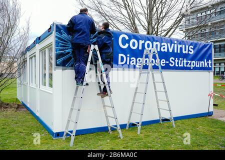 11 mars 2020, Bade-Wuerttemberg, Mannheim: Les artisans attachent une bannière avec l'inscription "Coronavirus Diagnosis base" aux conteneurs mis en place sur le terrain de l'hôpital universitaire. En raison de l'épidémie de coronavirus, l'hôpital universitaire a établi une base de diagnostic du coronavirus à partir d'aujourd'hui. Photo: Uwe Anspach/Dpa Banque D'Images