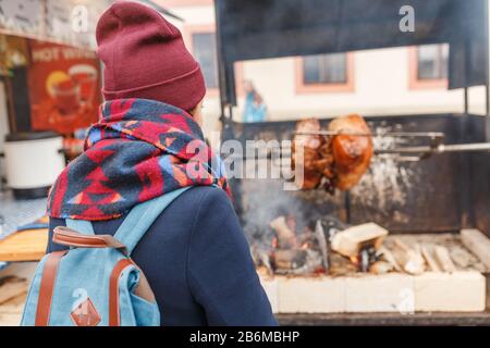 Femme touriste regarde la cuisine d'un genou de porc sur un feu ouvert à l'extérieur Banque D'Images