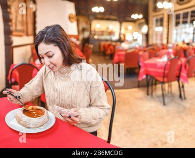 Femme mangeant une célèbre soupe traditionnelle hongroise et polonaise - goulash de boeuf servi dans un bol à pain Banque D'Images