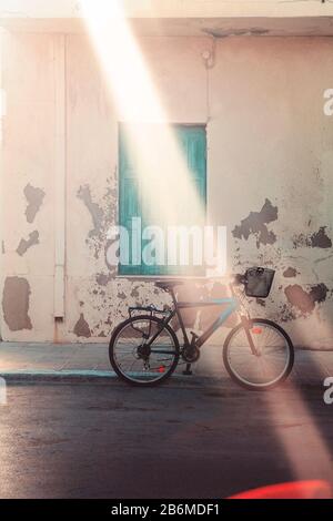 Illuminé par la bicyclette sunbeam stationné sur la route asphaltée à côté du mur de la barbu de vieux bâtiment avec fenêtre verte avec volets sur la rue de la ville Banque D'Images