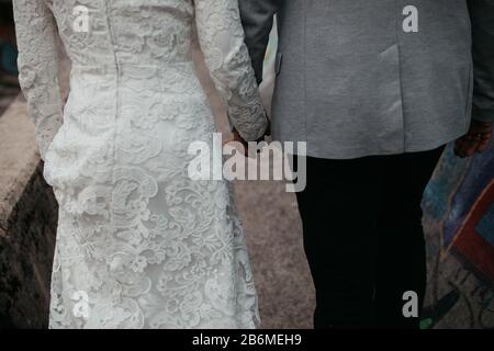Vue rapprochée des jeunes couples qui se joignent aux mains. Amour, confiance, famille, partenariat, bonheur. Tenir les mains sur la rue. Marcher ensemble. Banque D'Images