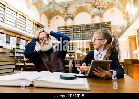 Livre électronique, livre, technologie, informatique par rapport au concept de livres d'impression traditionnels. Petite fille mignon tient ebook ou tablette et le montre à sa surprise et Banque D'Images