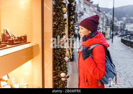 Une femme à Noël en regardant la fenêtre décorée du magasin Banque D'Images