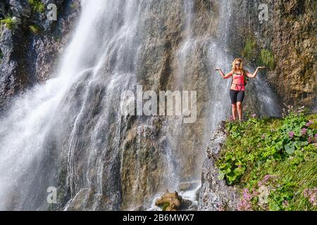 Femme posant devant la cascade de Dalfazer avec ses bras se propagent comme un signe d'échelle de Balance. Banque D'Images