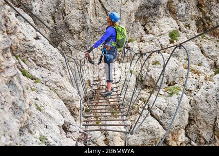 Femme sur via ferrata pont suspendu à Cesare Piazzetta klettersteig route, Dolomites montagnes, Italie. Banque D'Images