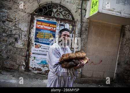 Jérusalem, Israël. 11 mars 2020. Un juif ultra-orthodoxe porte deux loafs de Challah, un type traditionnel de pain dans la cuisine juive, pendant les célébrations du quartier de Mea She'arim à Jérusalem pour marquer Purim, également appelé le Festival de Lots, une fête juive de type carnaval qui commémore la sauvegarde du peuple juif de Haman, Un responsable de l'Empire persan d'Achaéménide qui avait l'intention de tuer tous les Juifs, comme cela a été raconté dans le Livre d'Esther. Crédit: Ilia Yefimovich/Dpa/Alay Live News Banque D'Images