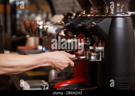 Mouture professionnelle de grains de café torréfiés frais. Porte-filtre sans fond pour barista avec café moulu. Préparation du café. Cof Banque D'Images