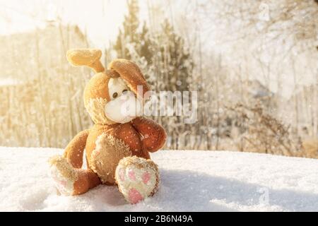 Jouet de fées de lapin lièvre assis sur une dérive de neige et attendant Pâques. Il neige et flocons de neige sont en chute libre. Superbe photo, espace de copie. Banque D'Images