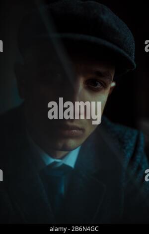 Portrait d'un homme à l'image d'un gangster rétro anglais des années 1920 vêtu d'un style boiteux. Vue par verre cassé. Banque D'Images