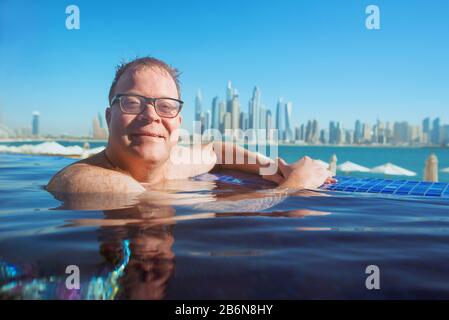 Portrait de l'homme rouge gai et détendu de l'europe dans des verres dans la piscine de Dubaï moderne (Emirats arabes Unis) et fond de mer Banque D'Images