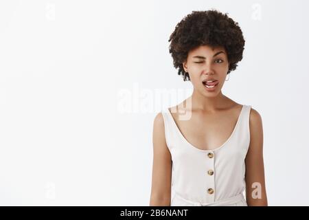 Photo en intérieur d'une charmante femme afro-américaine émotive et légère avec une coiffure en forme de curly qui colle la langue sensuellement et qui se fait virer Banque D'Images