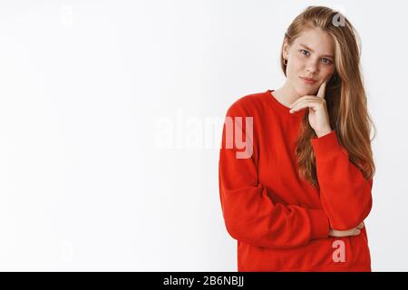 Prise de vue à la taille d'un jeune européen élégant et créatif femme avec de longs cheveux naturels équitables dans l'apprentissage de chandail rouge tête sur le doigt Banque D'Images