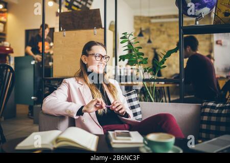 Rêvant une jolie dame pensant à des idées assis dans un café, profession créative. Thème moderne femme blogger. Jeune femme avec stylo à la main pensant à Banque D'Images