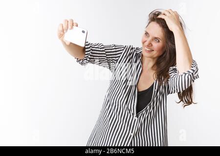 Toujours se sentir jeune et joli. Portrait d'une charmante femme d'âge moyen, confiante et dynamique, tenant son smartphone à main levée, prenant selfie Banque D'Images