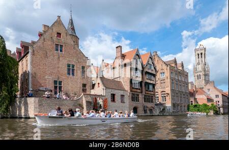 Bateaux touristiques sur les célèbres canaux de Bruges / Bruges, Belgique. Sur la droite se trouve le beffroi médiéval. Banque D'Images