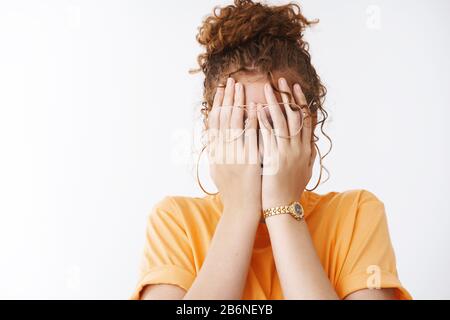 Une fille fatiguée qui cache le visage ne veut pas que tout le monde voit pleurer, couvre les yeux paumes portant des lunettes T-shirt orange, jouant PEEK-a-boo, attendez le comptage surprise de cadeaux Banque D'Images