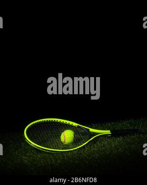 Raquette de tennis avec balles de tennis sur herbe avec fond noir et espace de copie. Banque D'Images
